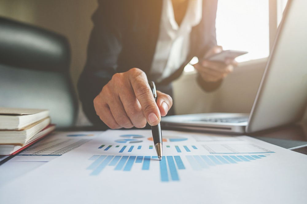 Pióro nad wydrukami z analizą finansową na jasnym biurku